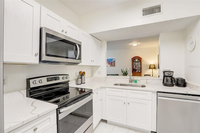 kitchen featuring light stone counters, stainless steel appliances, white cabinetry, and sink