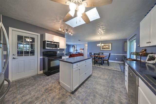 kitchen featuring white cabinets, a textured ceiling, stainless steel appliances, and a skylight