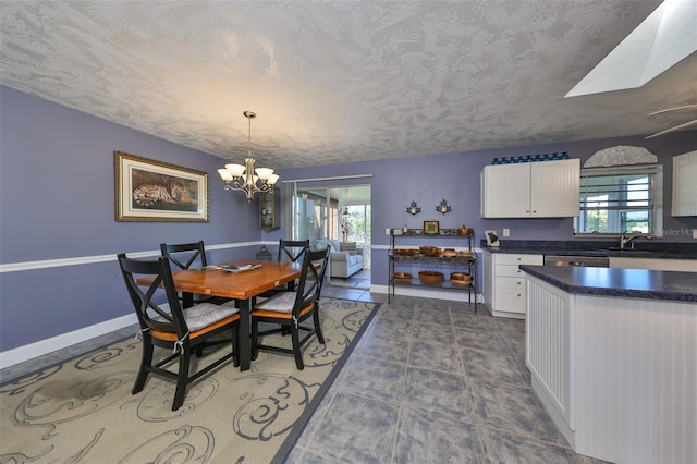 dining area featuring plenty of natural light, sink, a textured ceiling, and a skylight