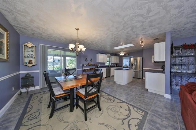 tiled dining room with a skylight, ceiling fan with notable chandelier, and a textured ceiling