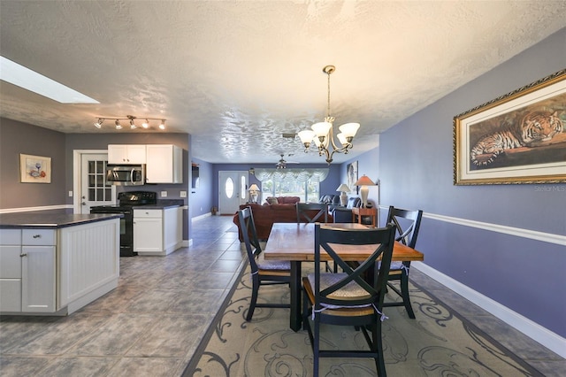 tiled dining space featuring a chandelier, a textured ceiling, and a skylight