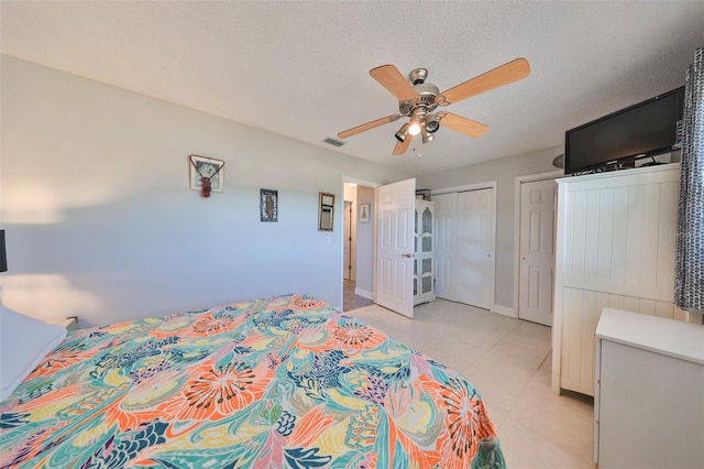 bedroom featuring ceiling fan, light tile patterned floors, a textured ceiling, and a closet