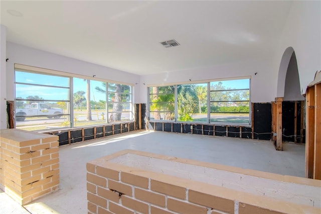 unfurnished living room featuring concrete flooring, visible vents, and plenty of natural light