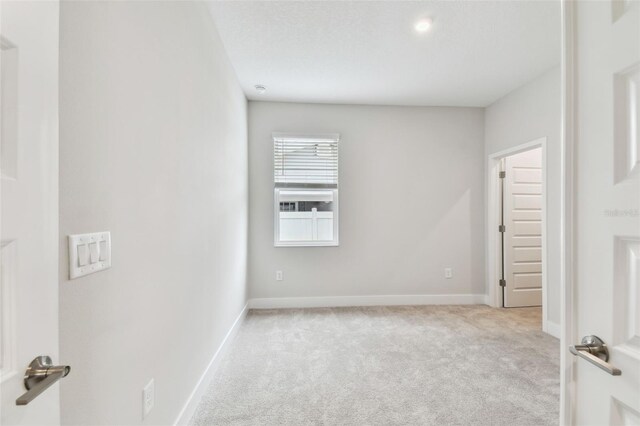 spare room featuring light colored carpet and baseboards