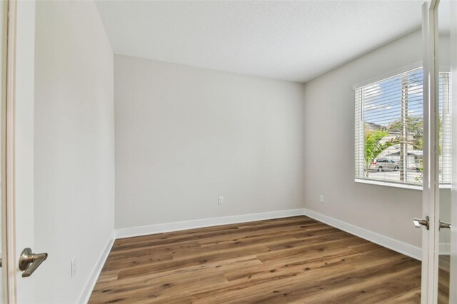 unfurnished room featuring baseboards, wood finished floors, and french doors