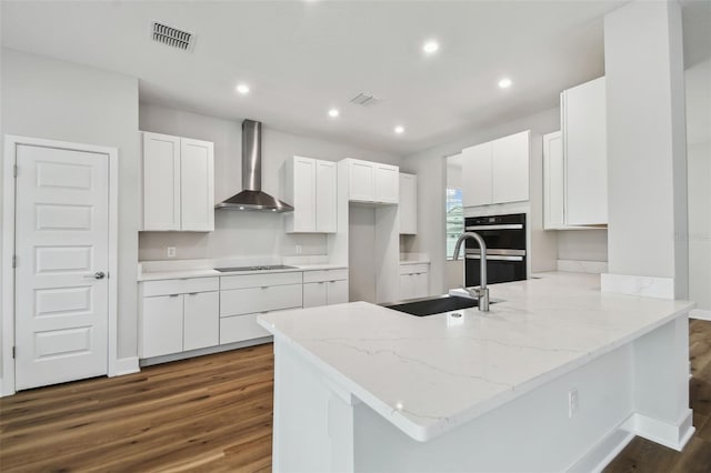 kitchen with black electric cooktop, a peninsula, a sink, visible vents, and wall chimney exhaust hood