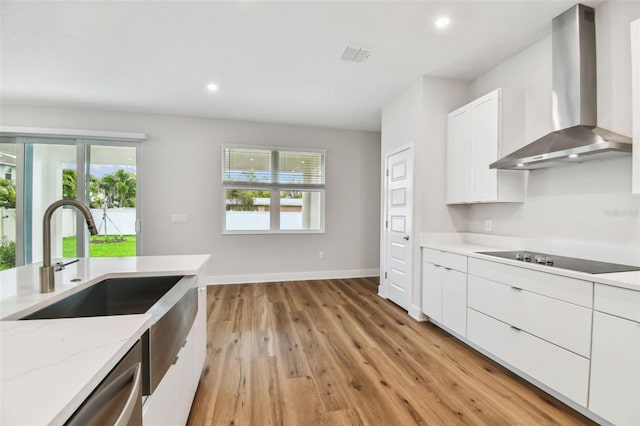 kitchen featuring black electric stovetop, light wood-style floors, white cabinets, light stone countertops, and wall chimney exhaust hood