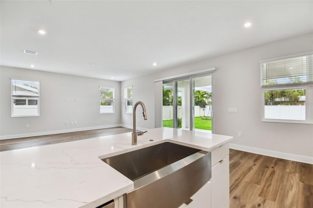 kitchen with light stone counters, recessed lighting, visible vents, a sink, and light wood-type flooring