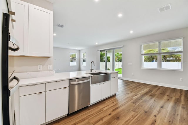 kitchen featuring visible vents, dishwasher, a sink, and white cabinetry