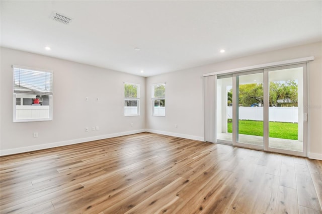 spare room featuring light wood-style floors, baseboards, and visible vents