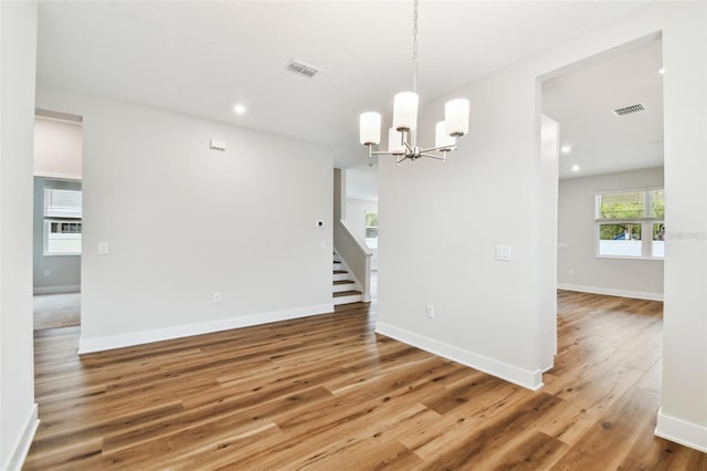 unfurnished dining area with baseboards, stairs, visible vents, and wood finished floors