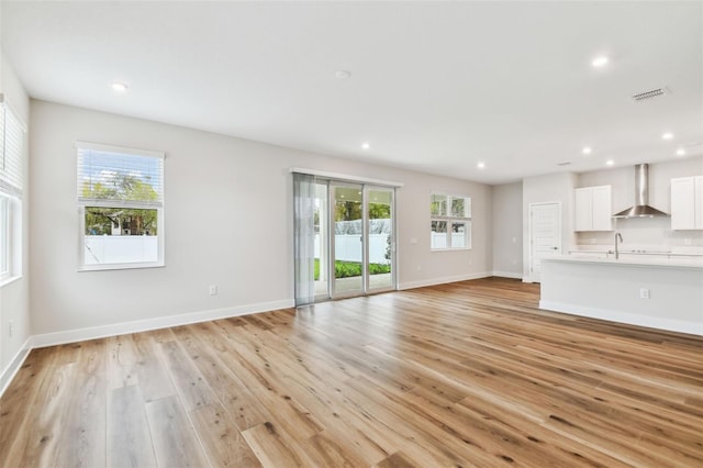 unfurnished living room with light wood-type flooring, plenty of natural light, and recessed lighting