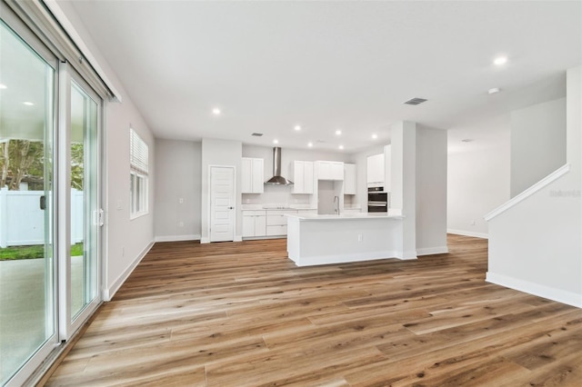 unfurnished living room featuring light wood-type flooring, visible vents, baseboards, and recessed lighting