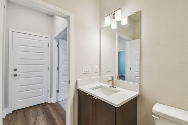 half bath featuring vanity, toilet, and wood finished floors