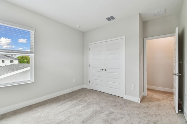 unfurnished bedroom featuring carpet, a closet, visible vents, and baseboards