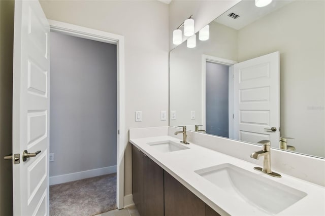 bathroom featuring double vanity, a sink, visible vents, and baseboards