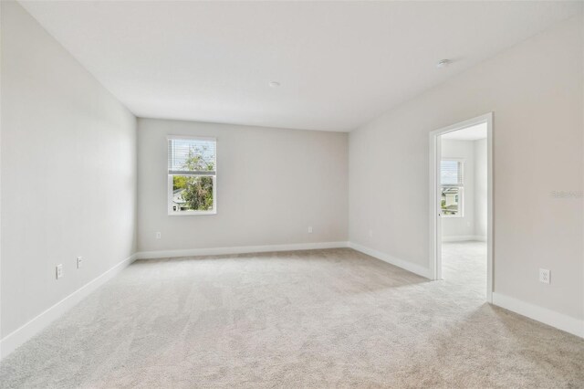 empty room featuring light carpet and baseboards