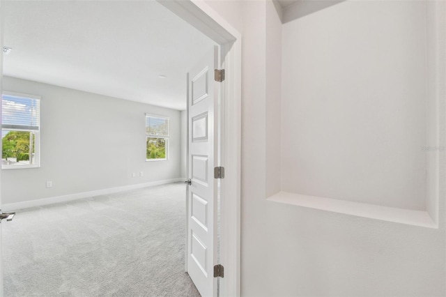 corridor with carpet flooring, a wealth of natural light, and baseboards