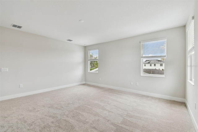 unfurnished room featuring baseboards, visible vents, and light colored carpet