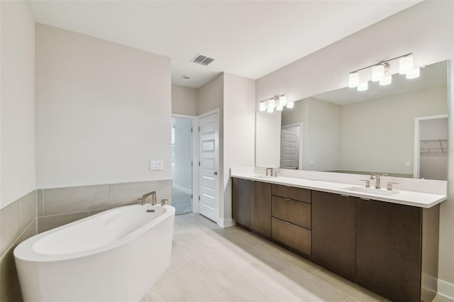 full bath with visible vents, a sink, a freestanding bath, and double vanity