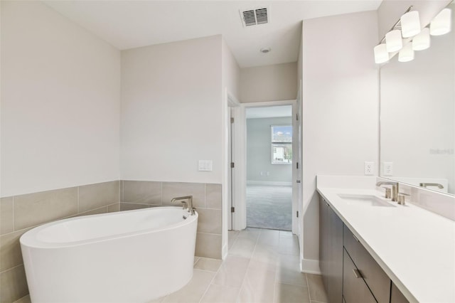 bathroom with visible vents, a soaking tub, tile patterned flooring, vanity, and tile walls