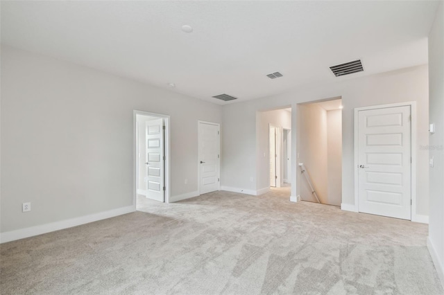 spare room with light carpet, baseboards, and visible vents