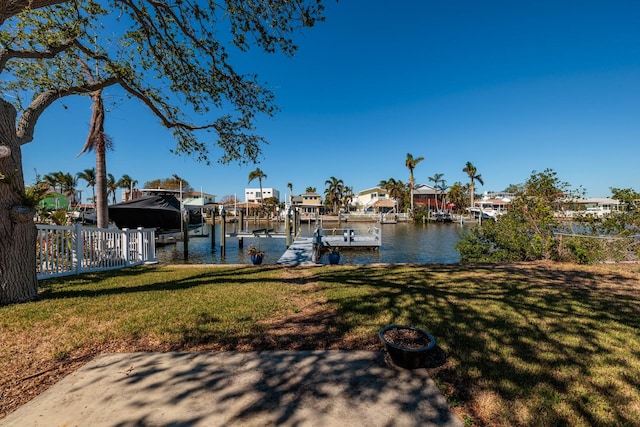 view of dock featuring a lawn and a water view