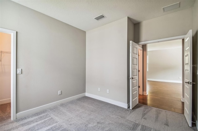 unfurnished bedroom featuring a textured ceiling, carpet floors, and a spacious closet