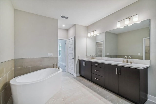 bathroom with a bathing tub, tile patterned flooring, vanity, and tile walls