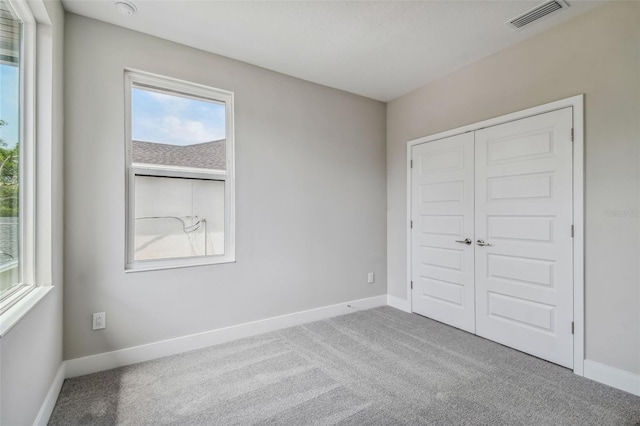 unfurnished bedroom featuring light colored carpet and a closet