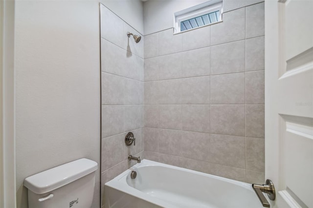 bathroom with toilet and tiled shower / bath