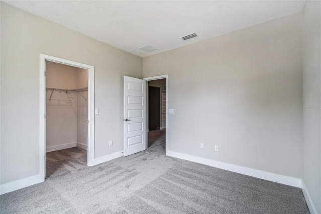 unfurnished bedroom featuring light colored carpet, a spacious closet, and a closet