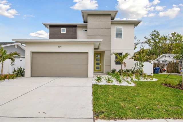 view of front of property with stucco siding, concrete driveway, an attached garage, fence, and a front lawn