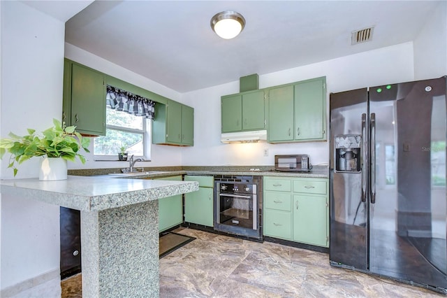 kitchen featuring kitchen peninsula, a breakfast bar, sink, black appliances, and green cabinetry