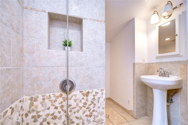 bathroom with tile patterned flooring, sink, a shower, and tile walls