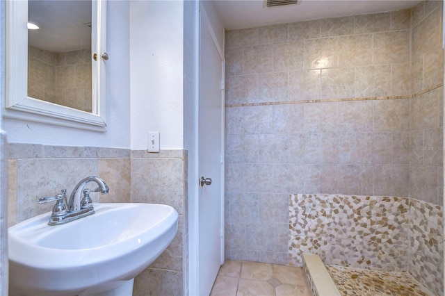 bathroom with tile patterned flooring, sink, and tile walls