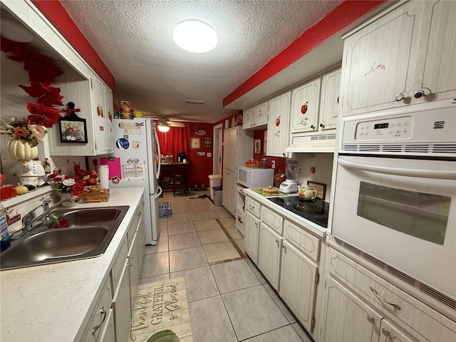 kitchen with a textured ceiling, white appliances, ceiling fan, sink, and light tile patterned flooring