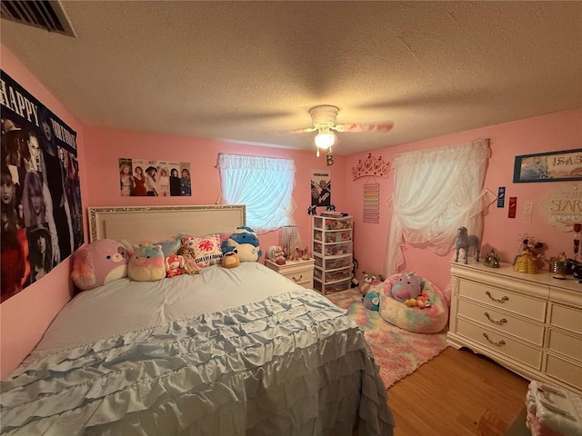 bedroom featuring wood-type flooring, a textured ceiling, and ceiling fan