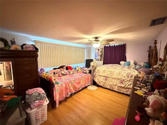 bedroom featuring ceiling fan, wood-type flooring, and a textured ceiling