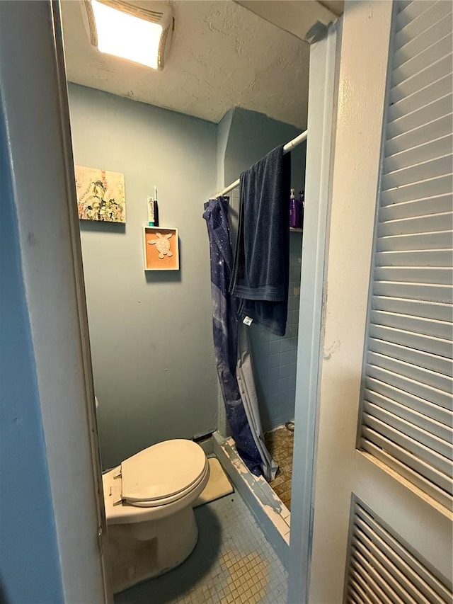 bathroom featuring tile patterned flooring, toilet, and curtained shower