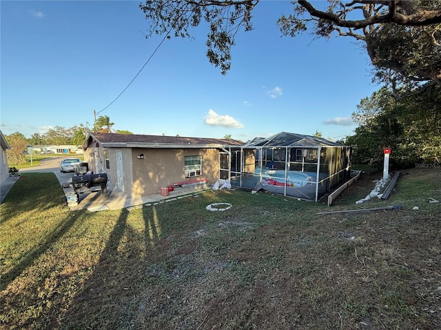 rear view of property featuring a lanai and a lawn