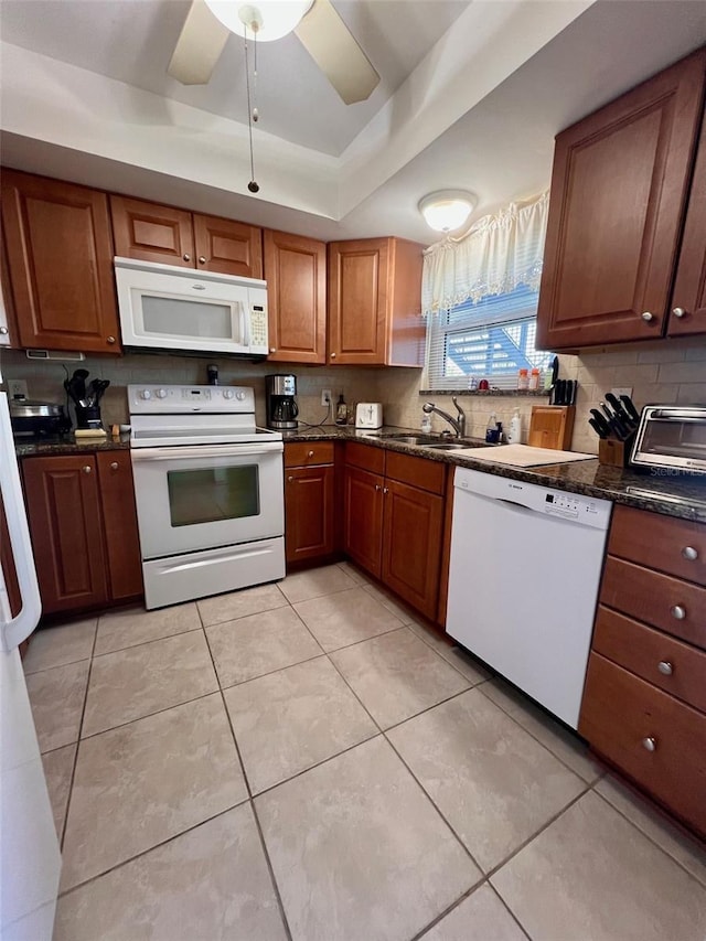 4660 Marine Pkwy Unit 202, New Port Richey, FL 34652 - kitchen with white appliances, a sink, a tray ceiling, tasteful backsplash, and brown cabinets