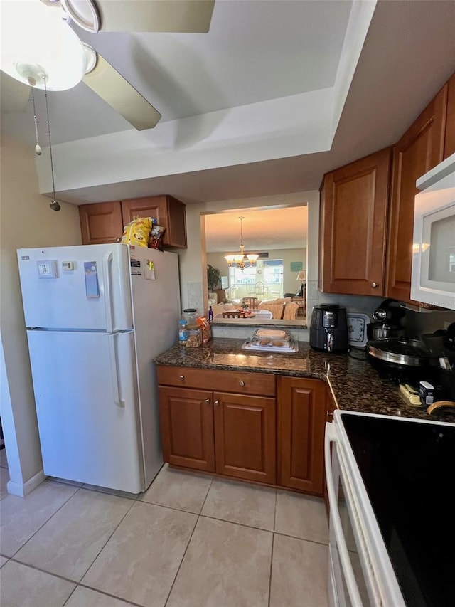 4660 Marine Pkwy Unit 202, New Port Richey, FL 34652 - kitchen featuring white appliances, brown cabinets, light tile patterned floors, a chandelier, and a raised ceiling