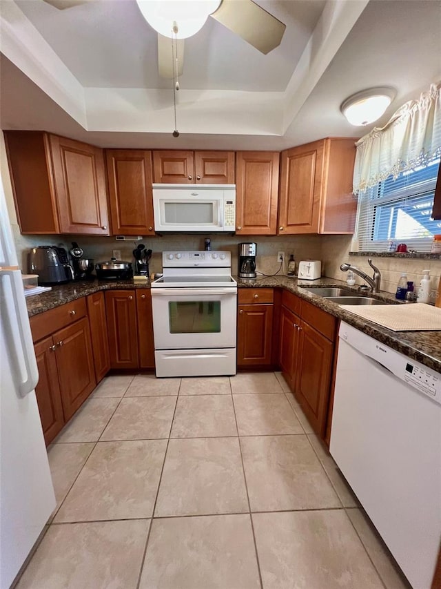 kitchen with a tray ceiling, ceiling fan, sink, and white appliances