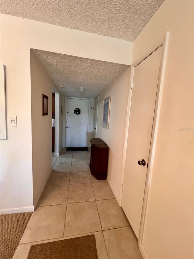 hallway with light tile patterned floors and a textured ceiling