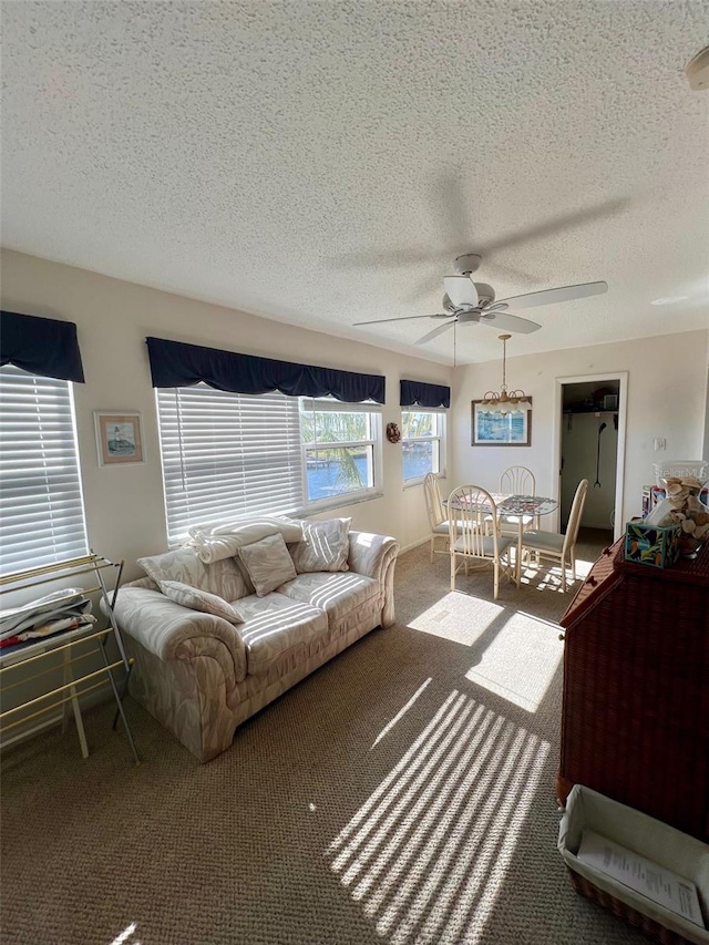 living room with ceiling fan, carpet floors, and a textured ceiling