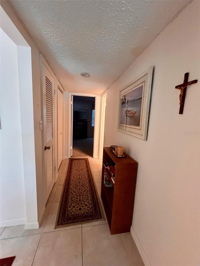 hallway with light tile patterned floors and a textured ceiling