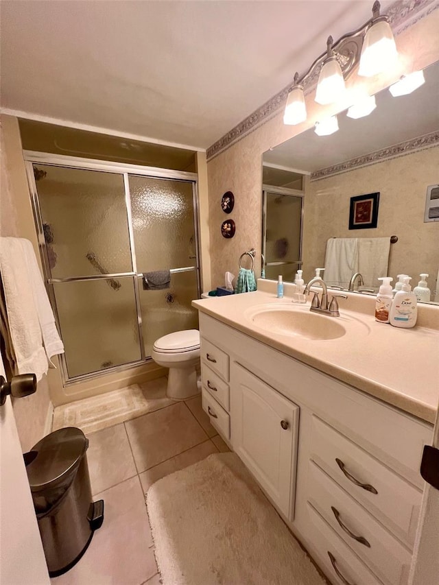 bathroom with tile patterned flooring, vanity, toilet, and a shower with shower door