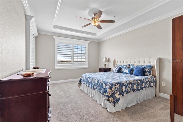 carpeted bedroom with ceiling fan, ornamental molding, and a tray ceiling