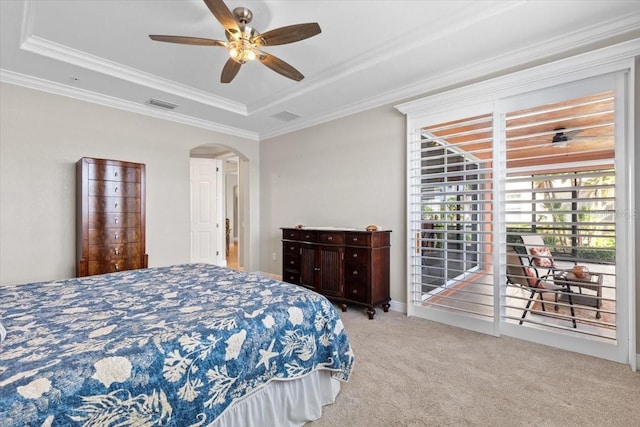 carpeted bedroom with ceiling fan, access to exterior, crown molding, and a tray ceiling